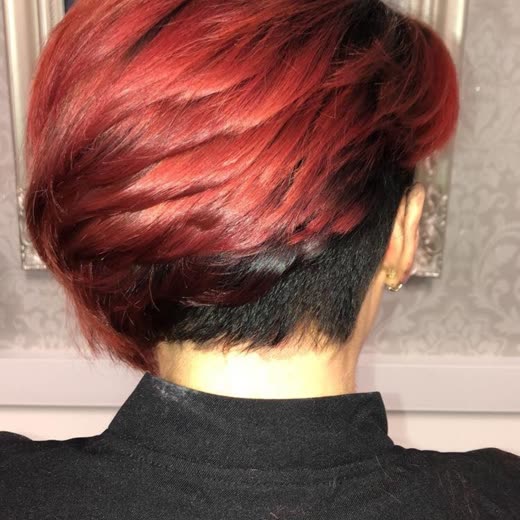 Back of a client's head with a short bright red pixie cut and a shaved nape